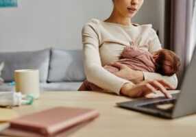 Close,Up,Of,Busy,Mother,Holding,Her,Baby,While,Sitting Close,Up,Of,Busy,Mother,Holding,Her,Baby,While,Sitting